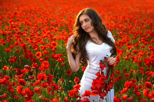 Menina bonita em um campo de papoula ao pôr do sol — Fotografia de Stock