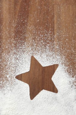 Minimalist Noel sahnesi, beş köşeli yıldız silueti, kar olarak ahşap ve un, kopyalama alanı