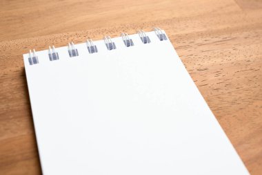 Boş bir sayfada, ahşap bir arka planda açılan sarmal defter. Öznel görünümü kapat.