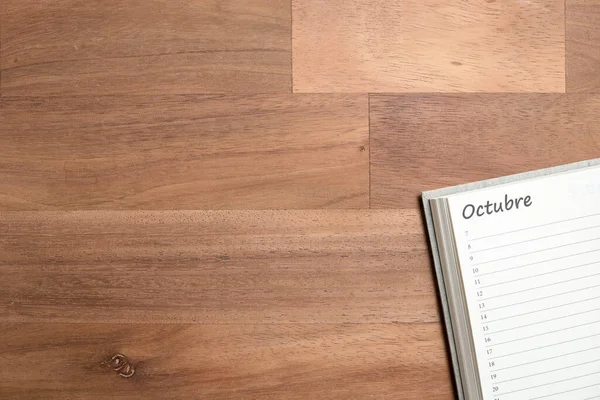 stock image Blank page of a daily planner in Spanish for the month of October, on a wooden background. View from above with copy space