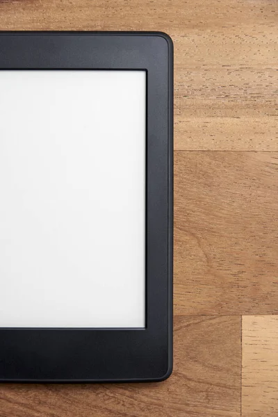 Closeup image of an electronic reader with blank screen on a wooden surface. Concepts of technology and modernity. Image with copy space.