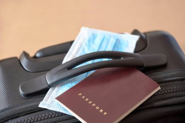 Bir bavul üzerinde pasaport ve yüz maskesi. Coronavirüs salgınının ortasında seyahat etme kavramı, Covid19 salgını. Kopyalama alanı olan resim.