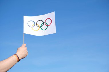 Açık havada el yapımı Olimpiyat Oyunları bayrağını tutan, açık havada mavi, beyaz ve kırmızı bir bilezik takan, Alman ulusal bayrağının renkleri. Kopyalama alanı olan resim.