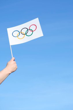 Güneşli bir günde açık havada el yapımı Olimpiyat Oyunları bayraklarıyla el ele tutuşmak. Kopyalama alanı olan resim.