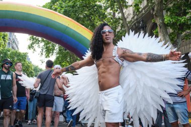 1 Kasım 2025, Buenos Aires, Arjantin: Beyaz melek kanatlı bir adam Onur Yürüyüşü sırasında şehir merkezinde bir gökkuşağı, LGBT sembolü yakınında poz verir.