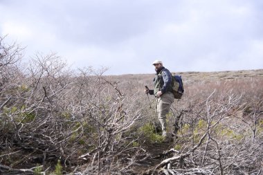 Bir yürüyüşçü mola sırasında Caviahue, Nequen, Arjantin 'deki eski elektrik santralinin şelalesine doğru yürürken kameraya bakar. Kış geldi..
