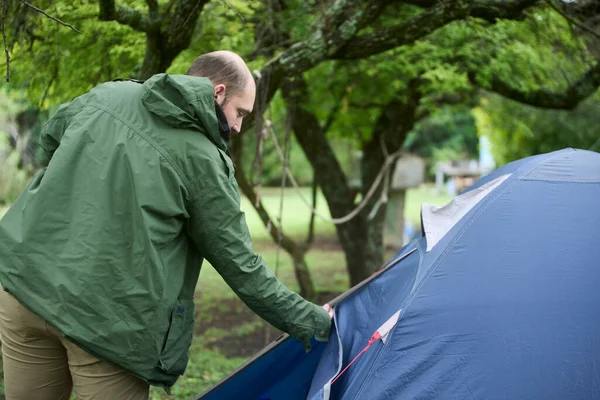 Genç yürüyüşçü doğa yürüyüşüne çıkmak için çadırının fermuarını kapatıyor. Kavram: açık hava tatillerinin keyfi.