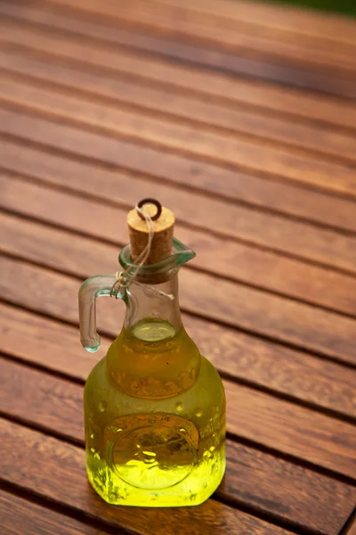 Olio d'oliva e ramo d'ulivo sul tavolo di legno — Foto Stock