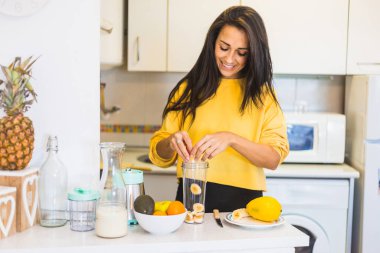 Genç ve güzel bir kadın sağlıklı bir içecek hazırlıyor.