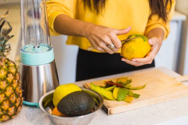 Smoothie için mango soyan genç bir kadın.