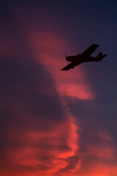 Ultralight aircraft flie over red flaming cloudscape — Stock Photo, Image