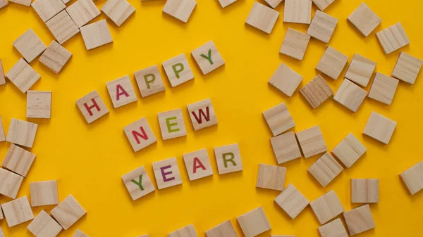 Mutlu yıllar ve mutlu Noeller. Sarı arka planda Scrabble harfleri. Kutlama tatili için harf kiremitleri.