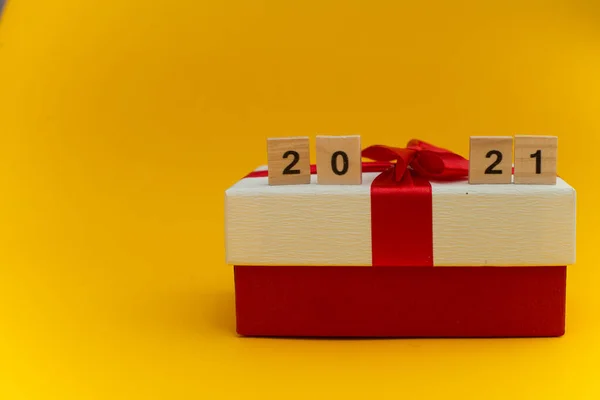 Mutlu yıllar ve mutlu Noeller. Sarı arka planda tatil hediyesi olan Scrabble numaraları. Hoşça kal 2020, hoş geldin 2021.