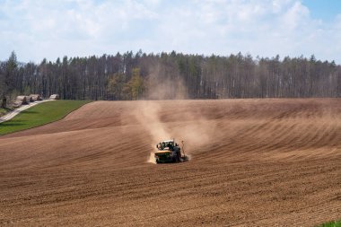 Sahadaki traktör kuru arazi yüzünden toz içinde.