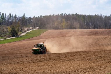 Sahadaki traktör kuru arazi yüzünden toz içinde.