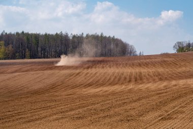 Sahadaki traktör kuru arazi yüzünden toz içinde.