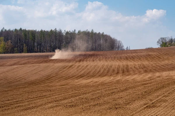 Sahadaki traktör kuru arazi yüzünden toz içinde.