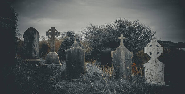 Ireland celtic cross at medieval church cemetery Old spooky cemetery . Haunted cemetery. Scary place. Old graves