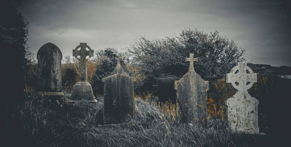 Ireland celtic cross at medieval church cemetery Old spooky cemetery . Haunted cemetery. Scary place. Old graves