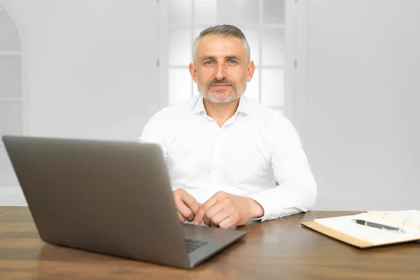 Middle age handsome businessman wearing tie sitting using laptop at the office with serious expression on face — Stock Photo, Image