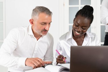 İki iş ortağı, genç Afrikalı kadın ve kıdemli beyaz adam, konferansta proje hakkında yeni fikirlerle çalışıyorlar.