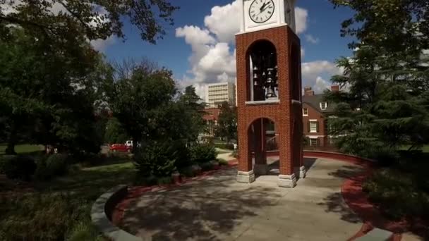 Una pequeña torre de reloj frente a un edificio de ladrillo — Vídeos de Stock