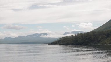Arka planda dağ olan bir su kütlesinin üzerindeki köprü.