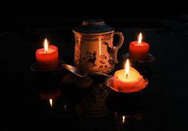 Çin çayı, mumların etrafında güzel bir çaydanlıkta servis edilir.