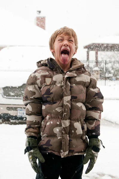 Chico pegando lengua hacia fuera en nieve —  Fotos de Stock