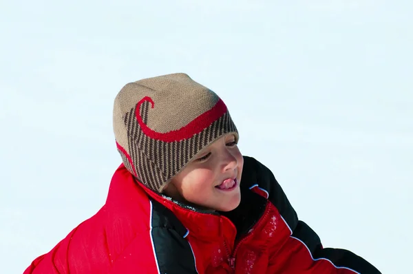 Netter Junge spielt mit herausgestreckter Zunge im Schnee. — Stockfoto