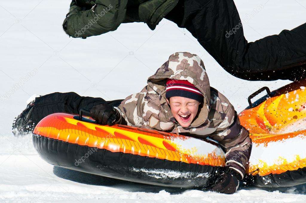 Young boy laughing on a snow tube