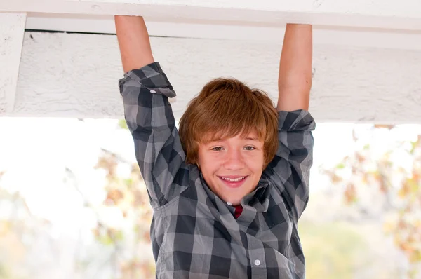 Handsome boy hanging from his arms. — Stock Photo, Image