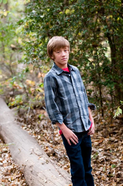 Young handsome boy standing on a log outdoors. — Stock Photo, Image