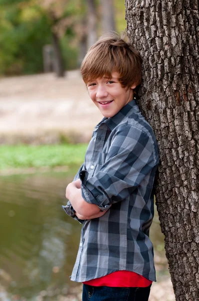 Vacker teen pojke lutar på träd. — Stockfoto