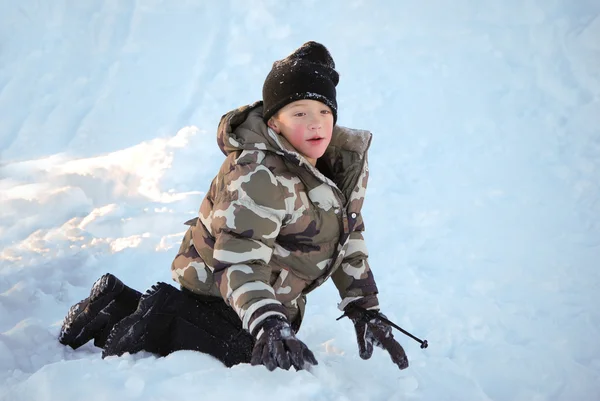 Netter kleiner Junge in Camo-Skijacke spielt im Schnee. — Stockfoto