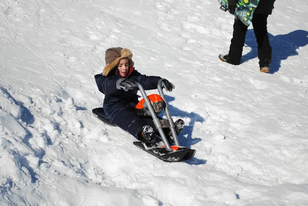 Carino bambino cavalcando moto nella neve all'aperto . — Foto Stock