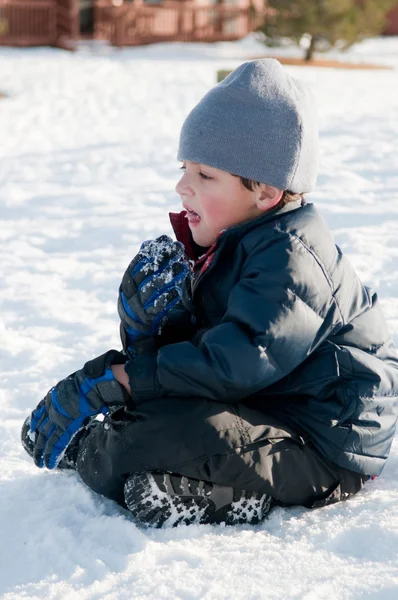 Entzückender kleiner Junge in Marinemantel sitzt im Schnee. — Stockfoto