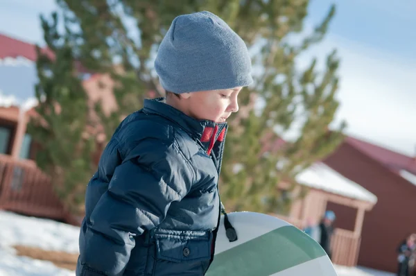 Bedårande liten pojke promenader i snön bär släde med marinblå jack — Stockfoto