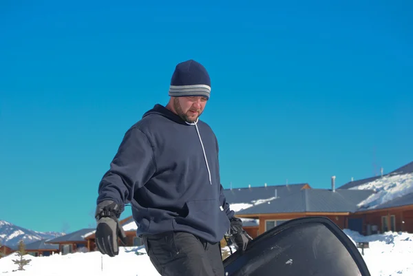 Homem em tobogã carregando um trenó de neve . — Fotografia de Stock