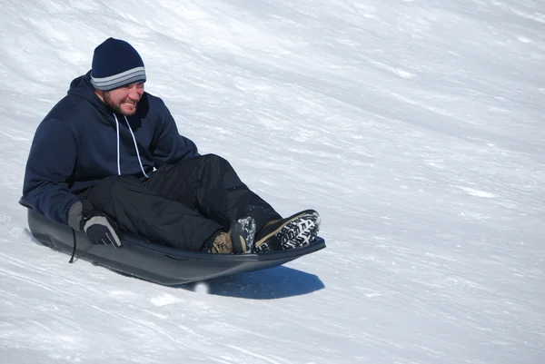 Άνθρωπος με έλκηθρο κάτω από ένα snowhill — Φωτογραφία Αρχείου