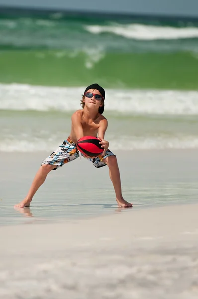 Cute little boy catching football on beach. — Stock Photo, Image
