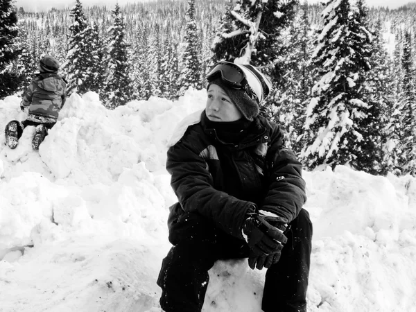 Schwarz-Weiß eines Jungen, der im Schnee sitzt. — Stockfoto