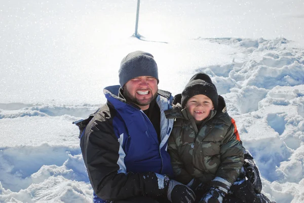 Vader en zoon zitten in de sneeuw — Stockfoto