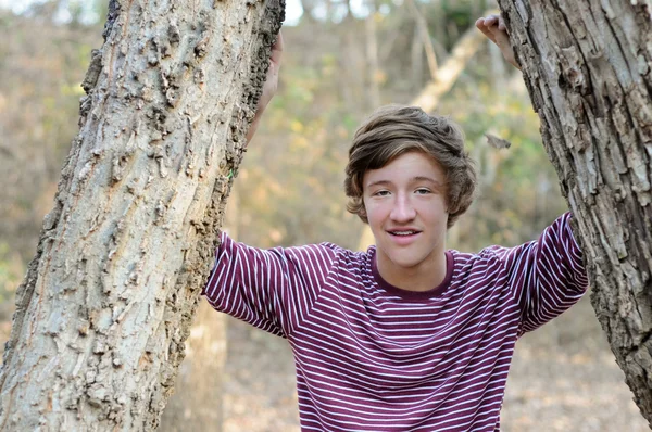 Pohledný teen chlapec venku mezi stromy. — Stock fotografie