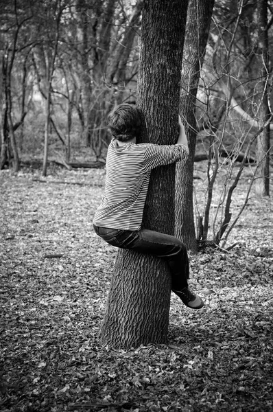 Tiener jongen knuffelen van een boom. — Stockfoto