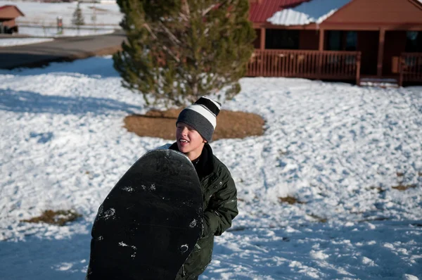 Jonge jongen in de sneeuw holding slee. — Stockfoto