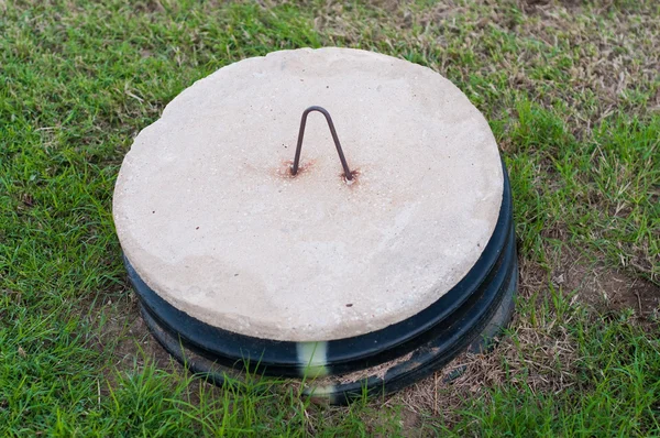 Tapa del tanque séptico en medio de un patio . — Foto de Stock