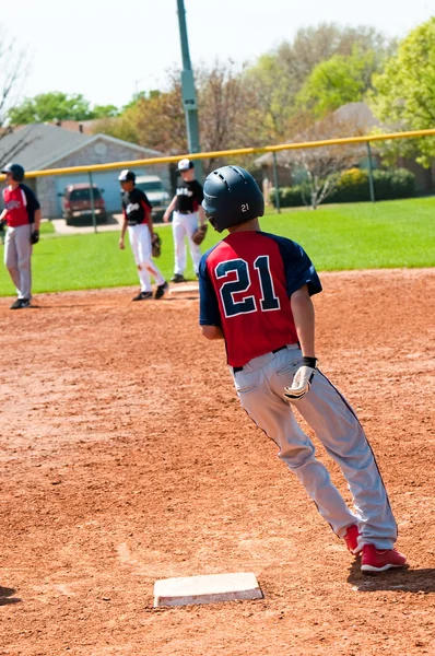 Teenage baseball boy running around first base. — Stock Photo, Image