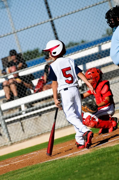 Youth baseball pojke på att bat tittar på kannan. — Stockfoto