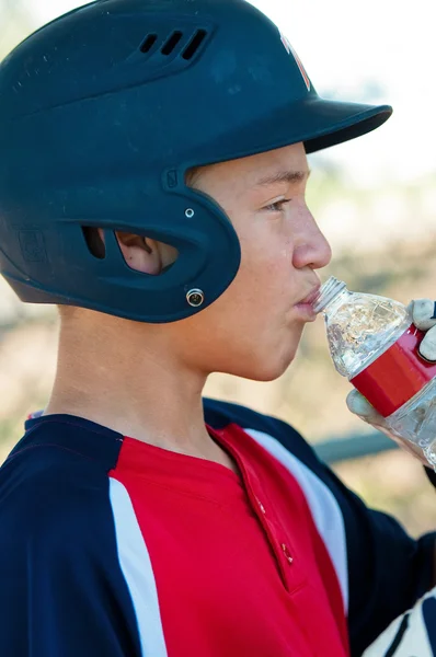 teenage baseball player drinking water